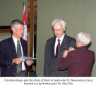 Christine Meyer pins the Order of Merit in Gold onto Dr. Alexander Lang handed out by Ambassador Dr. Otto Ditz