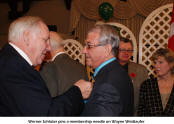 Werner Schlter pins a membership needle on Wayne Wettlaufer